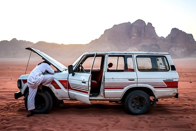 Muž opravuje auto na púšti 